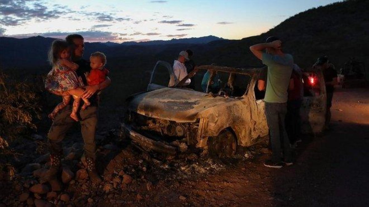 Varios miembros de la comunidad LeBarón inspeccionan uno de los vehículos atacados, este martes.-HERIKA MARTINEZ (AFP)