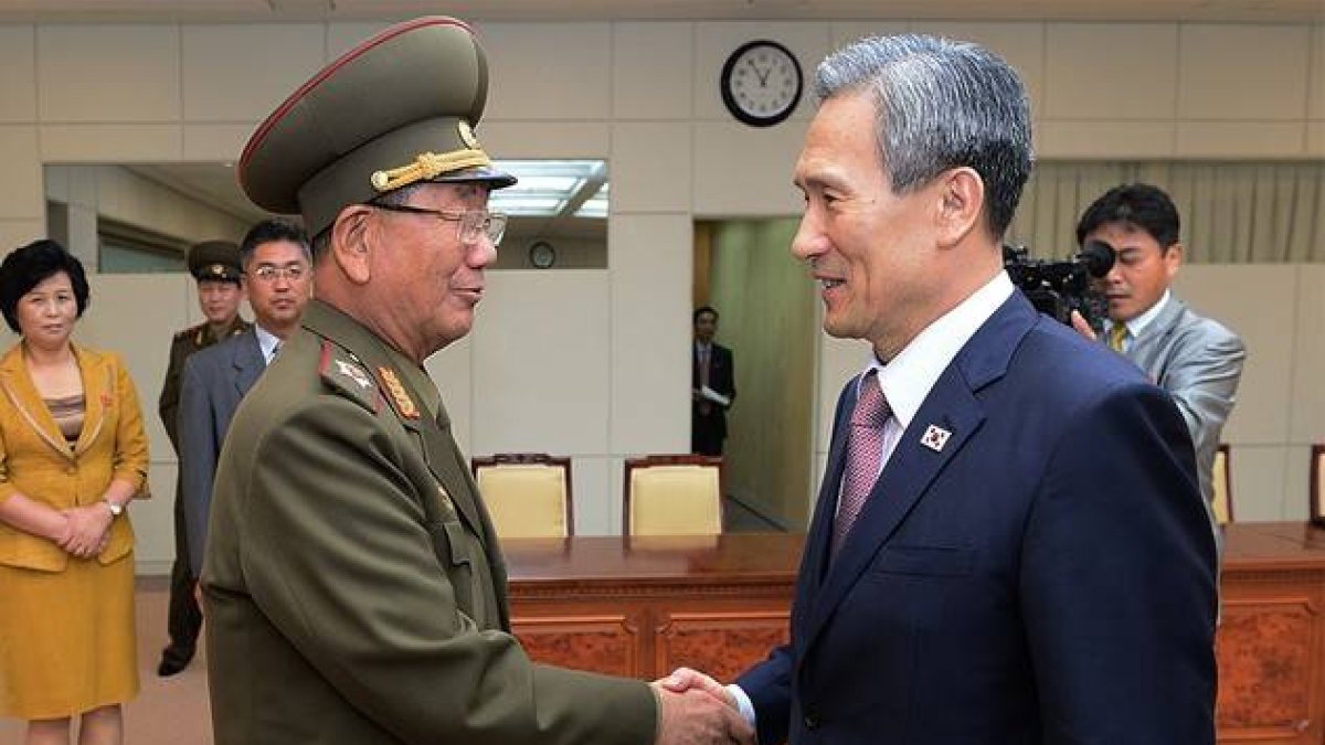 El ministro surcoreano de Unificación, Kim Kwan-jin, a la derecha, da la mano a Hwang Pyong So, responsable norcoreano, tras alcanzar el acuerdo para rebajar la tensión.-AP