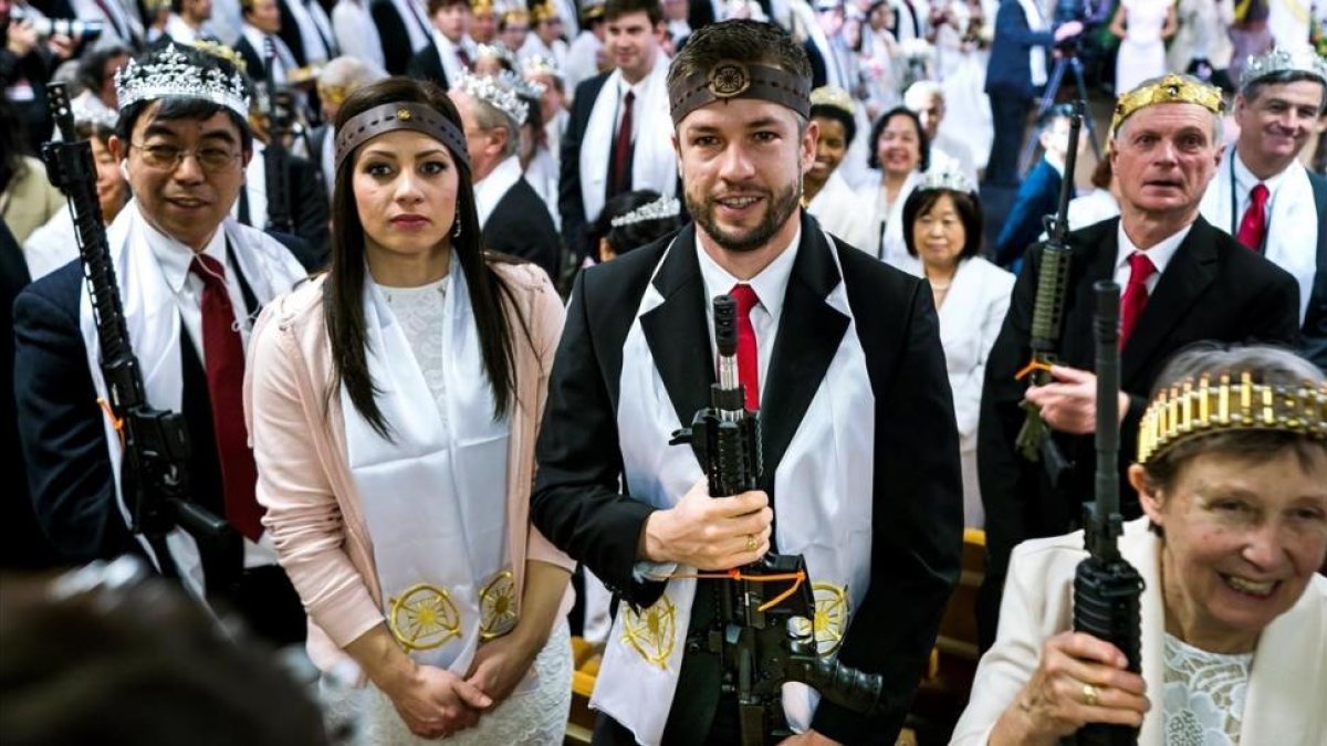 Devotos de la Iglesia de la Paz Mundial y la Unificación, en Pensilvania, con fusiles de asalto y coronas de balas, en una ceremonia de bendición para volver a santificar sus matrimonios-JIM LO SCALZO