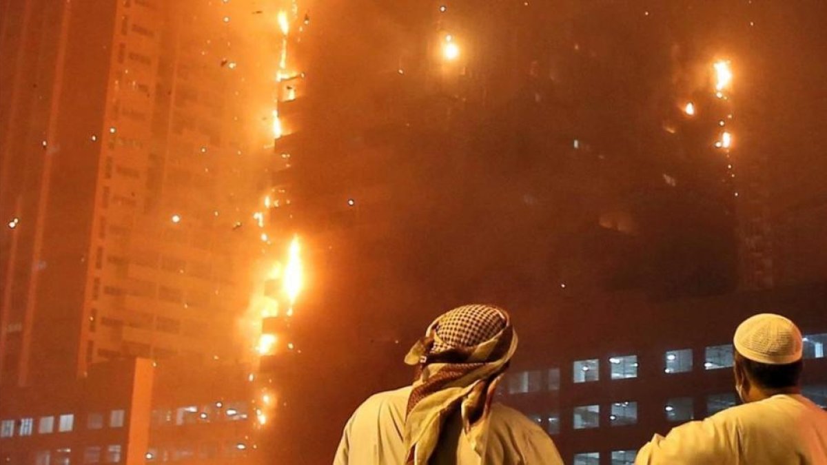 Dos oficiales emiratíes miran como se estiende el fuego a lo largo del edificio.-Kamran Jebreili