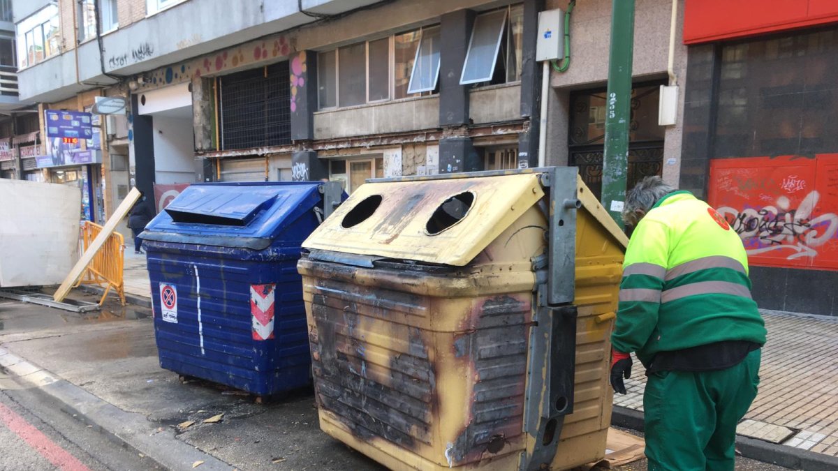 Un operario municipal repinta uno de los contenedores incendiados anoche en la calle Vitoria. RAÚL OCHOA