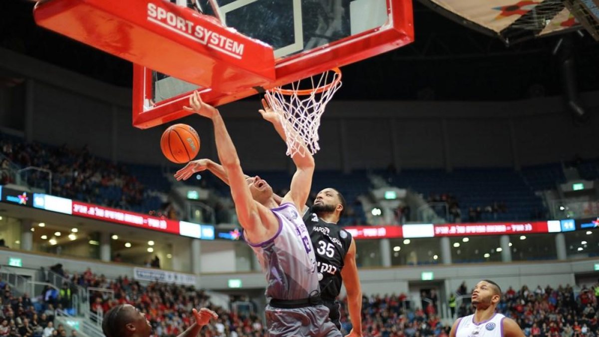 Thomas evita la canasta de Apic, ayer, en Jerusalén.-FIBA