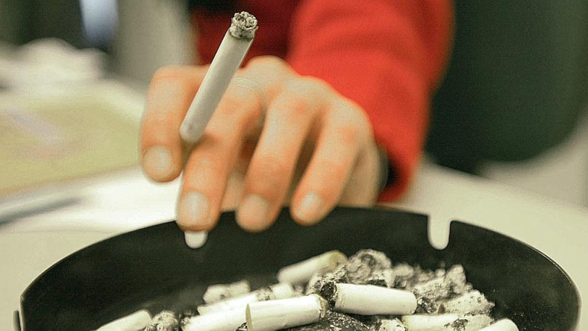 Una persona sostiene un cigarrillo junto a un cenicero.-ISRAEL L. MURILLO