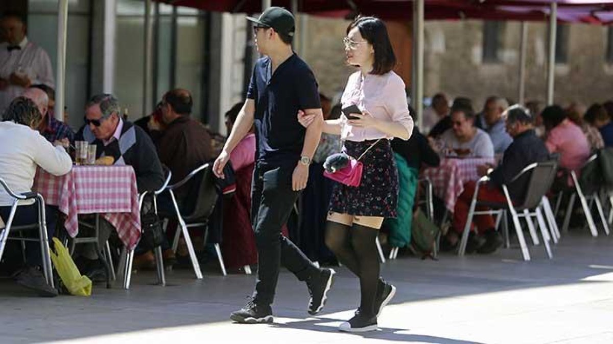 Dos turistas asiáticos pasean frente a la terraza de un restaurante a los pies de la Catedral, llena gracias al buen tiempo de ayer.-RAÚL G. OCHOA