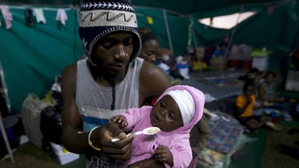 Un extranjero alimenta a su bebé en una tienda donde han sido realojados en Isibingo, en el sur de Durban, este lunes.-Foto: REUTERS / ROGAN WARD