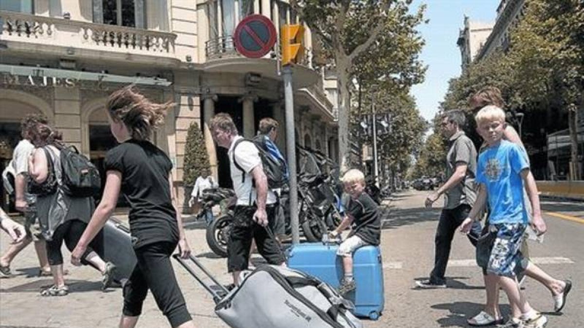 Turistas con maletas rumbo a su alojamiento recorren el paseo de Gràcia.-Foto: JOAN CORTADELLAS
