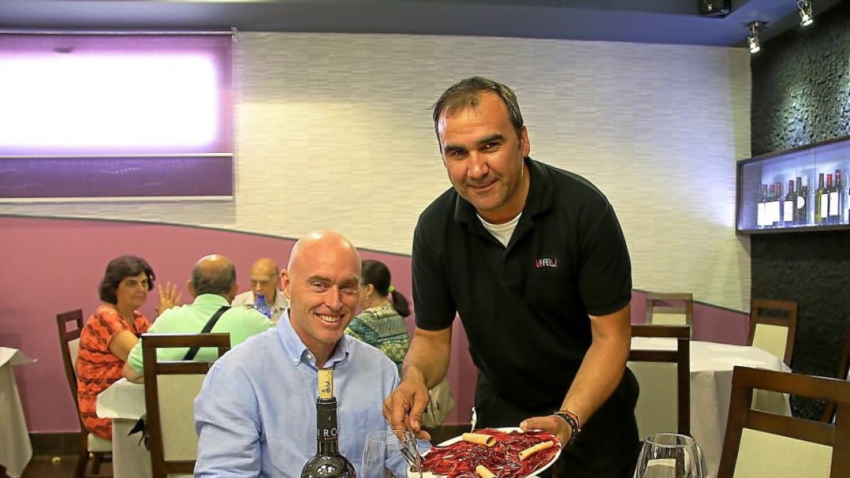 PLATOS CASEROS. José Luis Toral sirve un plato de cecina a Hansen en el comedor del restaurante Felu, de Portillo (Valladolid).-M. T.