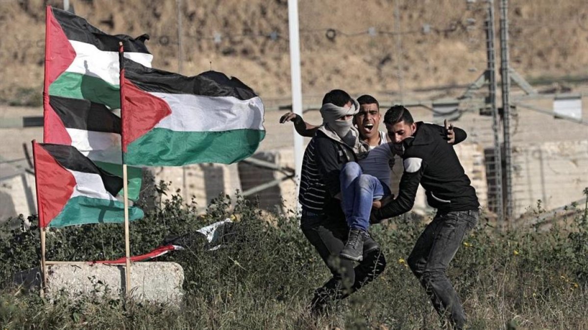 Manifestantes evacuan a un herido en las protestas de este sábado en Gaza.-/ EFE / MOHAMMED SABER