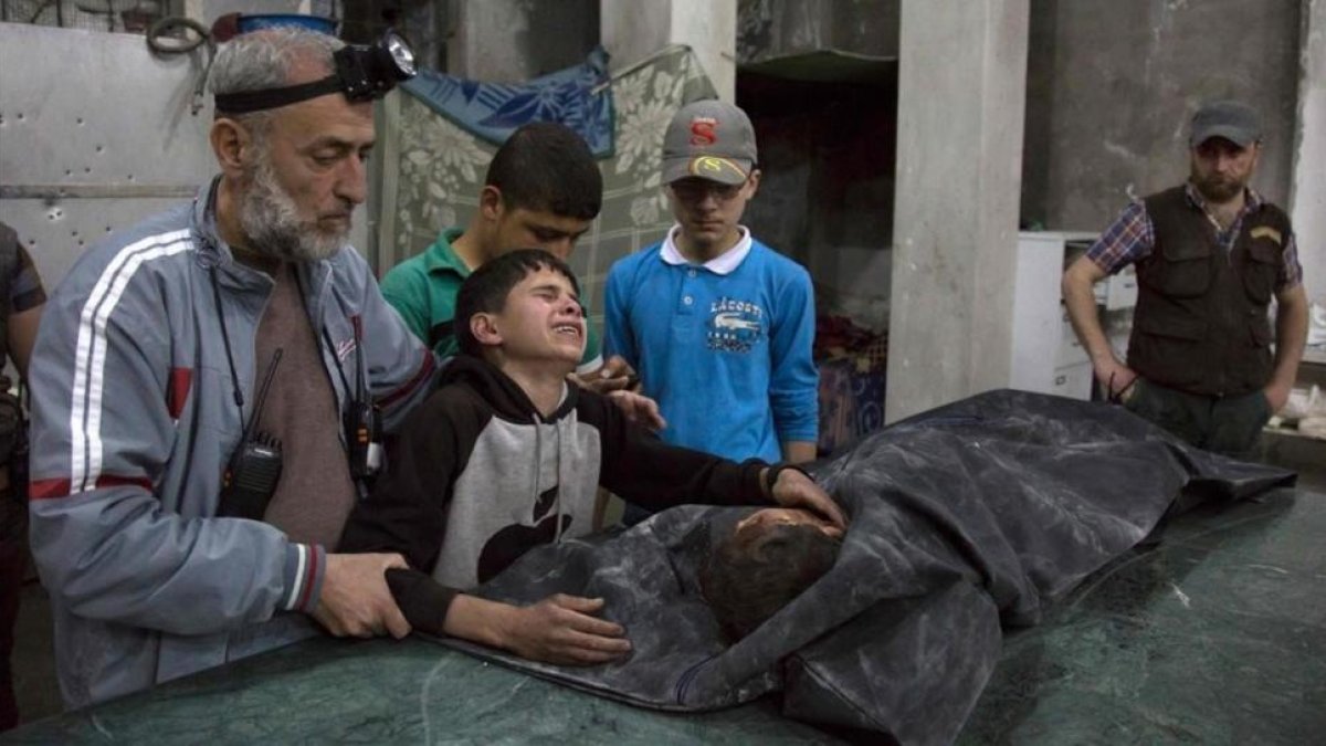 Un niño sirio es consolado mientras llora junto al cuerpo de su hermano pequeño que murió en el ataque aéreo del régimen de Bashar al Asad al hospital de Al Quds.-AFP / KARAM AL-MASRI