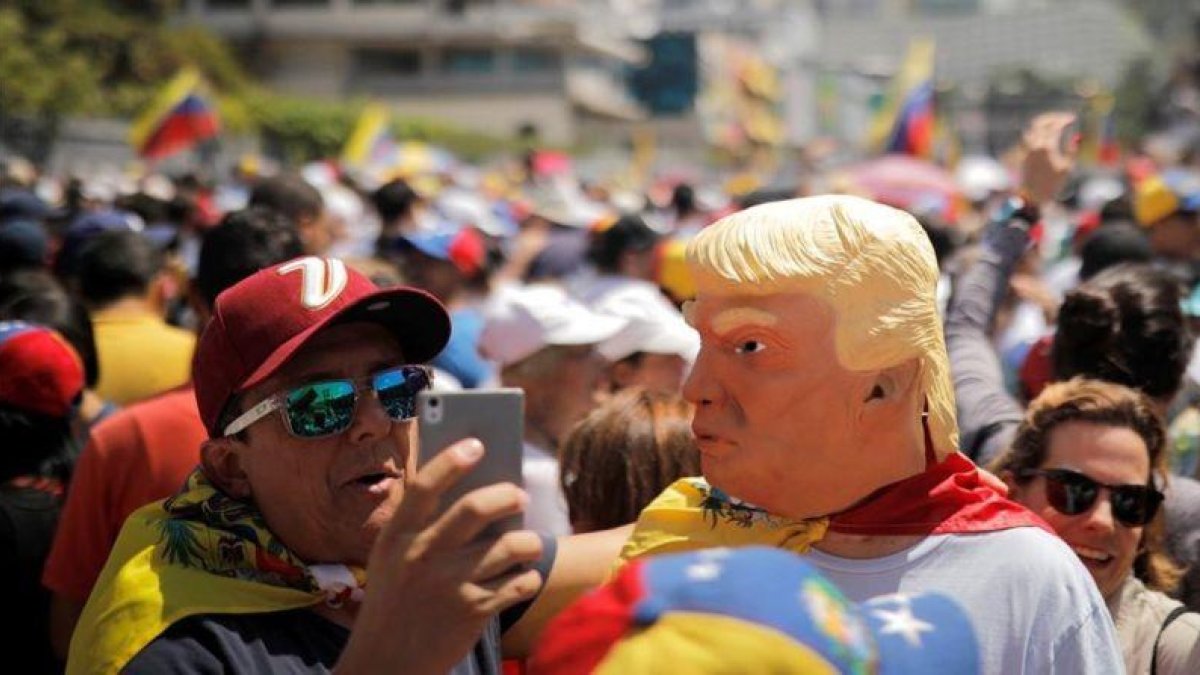 Manifestantes a favor de Maduro con caretas de Donald Trump, este sábado en Caracas.-REUTERS / CARLOS BARRIA