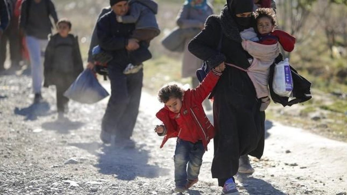 Una familia de refugiados se dirige a la frontera de Macedonia con Serbia.-