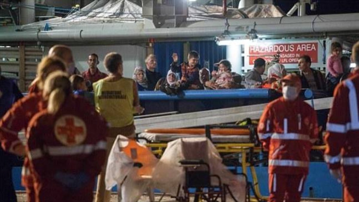 Los inmigrantes supervivientes de un naufragio llegan este jueves a tierra firme tras ser salvados por las autoridades de Libia, mientras los equipos médicos se llevan los cuerpos de los fallecidos.-REX SHUTTERSTOCK/ANTONIO MELITA