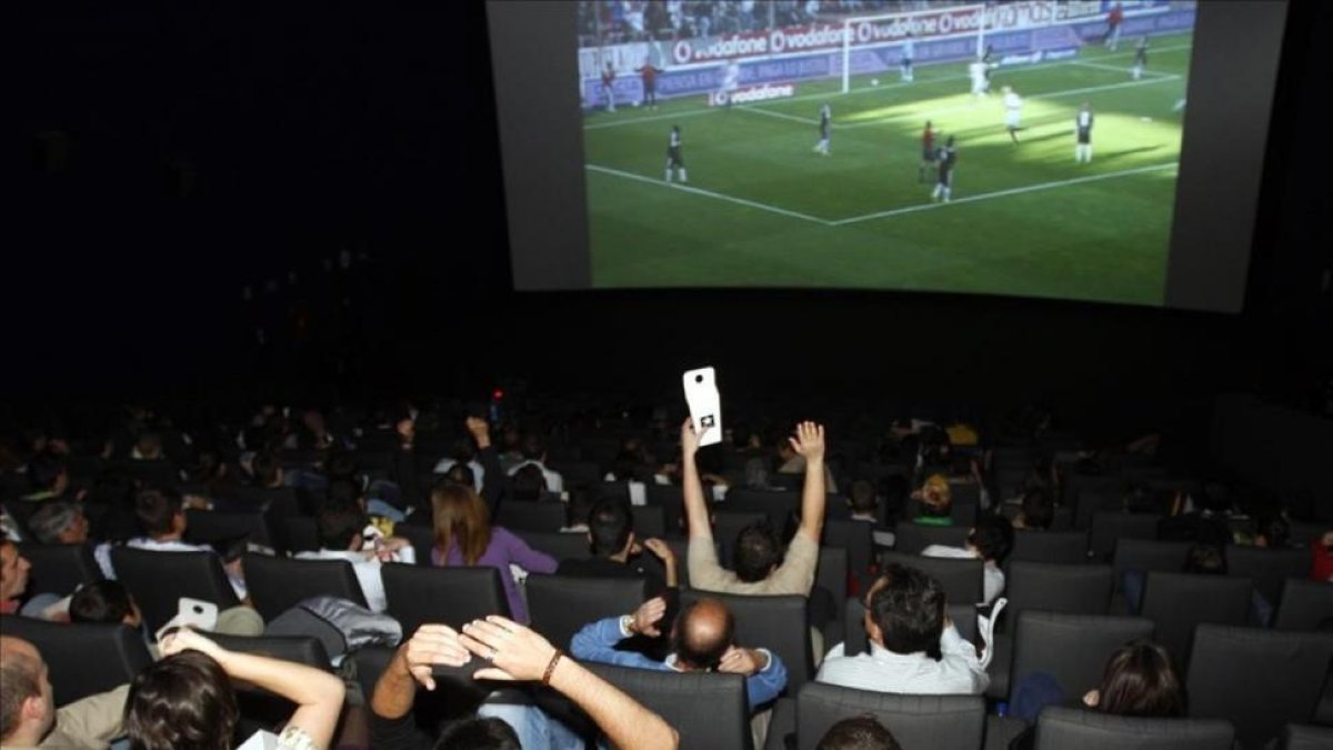 Aficionados siguiendo un partido de fútbol televisado en un cine madrileño.-AGUSTÍN CATALÁN