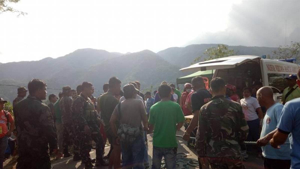 Fotografía cedida por la Estación de Policía del municipio de Carranglan donde se ve a ciudadanos filipinos, soldados y policías sosteniendo una cuerda para recuperar los cuerpos de las víctimas del accidente.-EFE