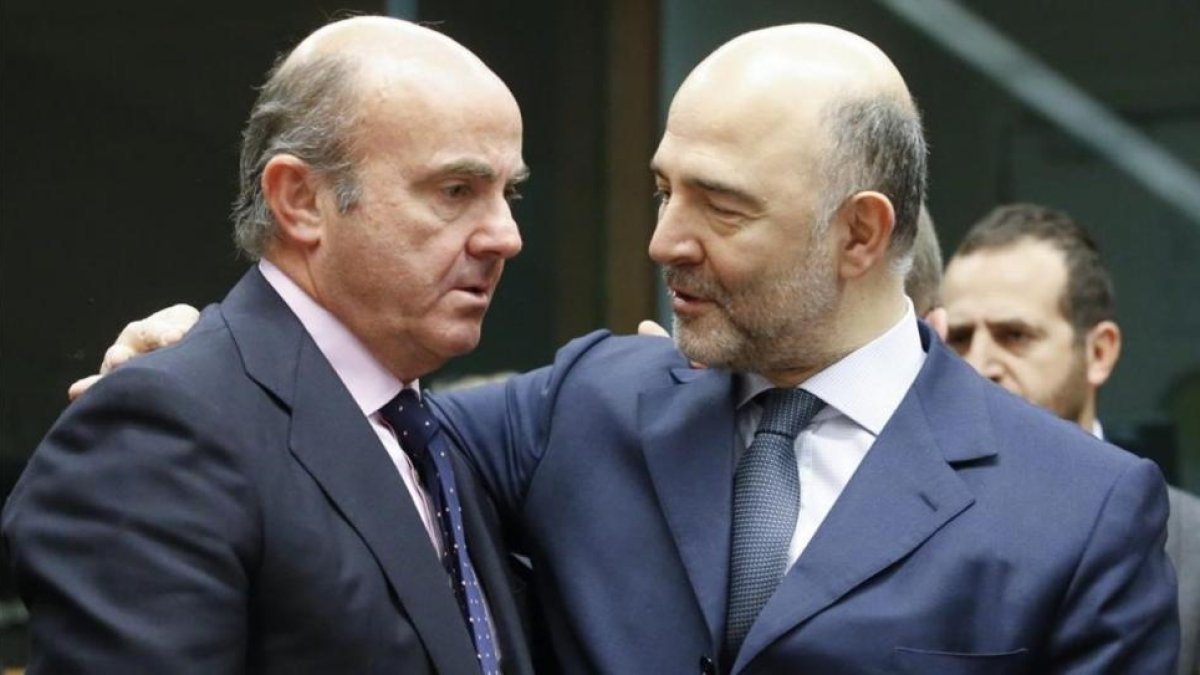 El ministro espanol de Economia, Luis de Guindos, conversa con el comisario europeo de Asuntos Economicos, Pierre Moscovici.-EFE / OLIVIER HOSLET