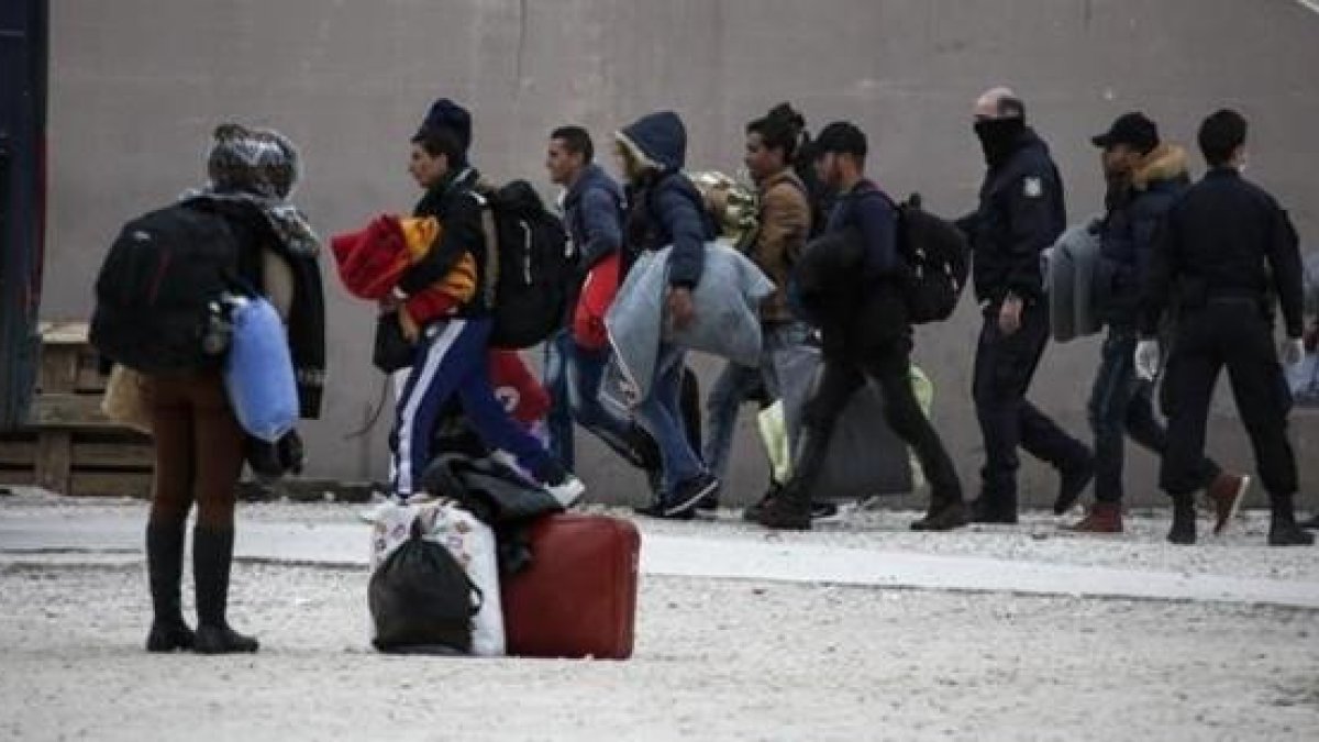 La policía griega escolta a inmigrantes en el exterior de un estadio en el sur de Atenas.-AP / YORGOS KARAHALIS.