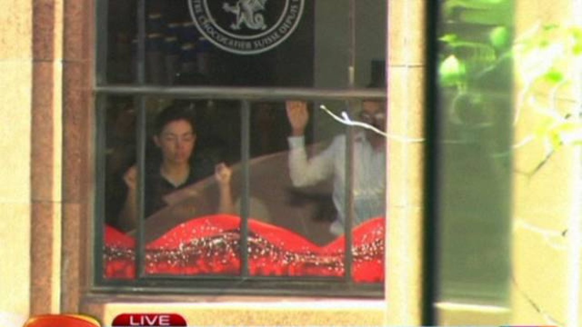 Dos de los rehenes, contra las ventanas del café Lindt Chocolate Cafe, del centro de Sídney, este lunes.-Foto: AP
