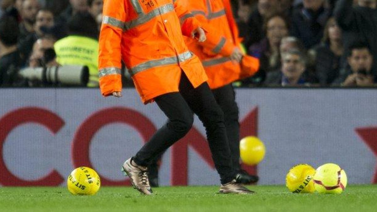 Empleados del Barça retiran los balones amarillos lanzados por un sector del público.-JORDI COTRINA