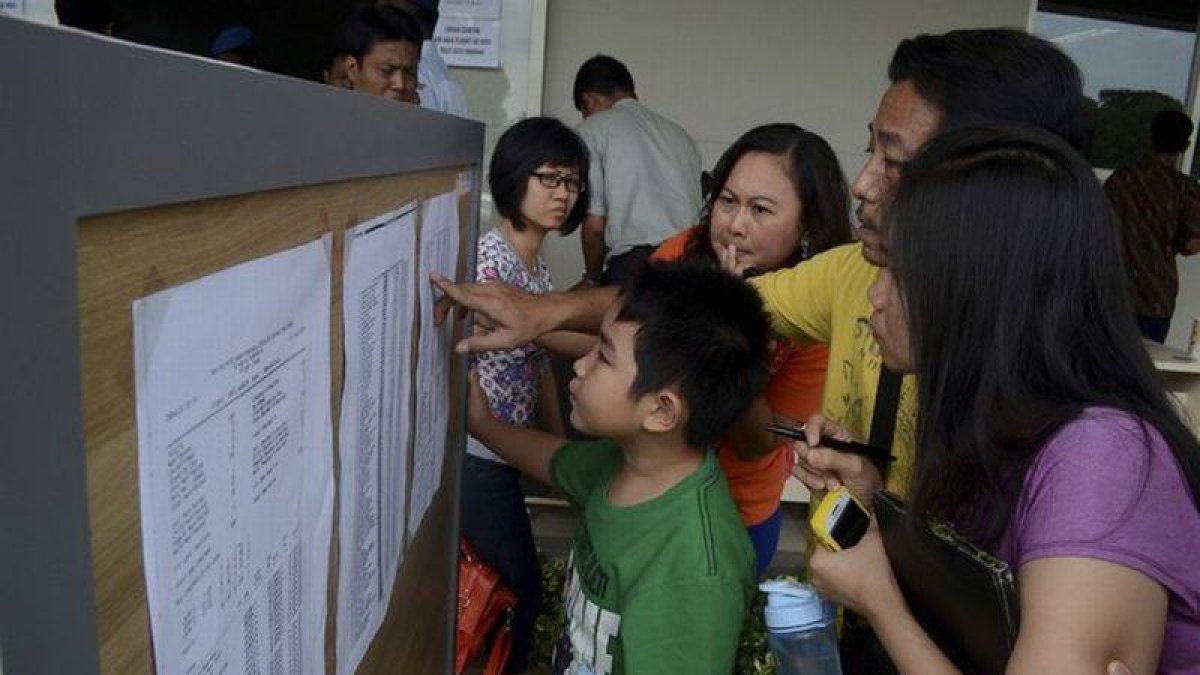 Familiares de los pasajeros del vuelo desaparecido miran una lista en el aeropuerto de Surabaya, este domingo.-Foto: ANTARA FOTO / REUTERS