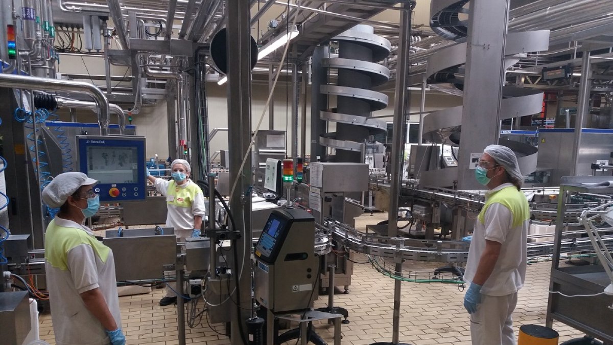 Trabajadores de la fábrica de Pascual en Aranda guardando la distancia de seguridad y con mascarilla. L. V.