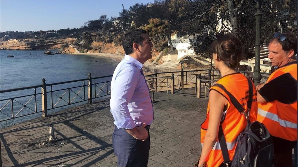 Tsipras habla con dos miembros de protección civil en Mati.-AP