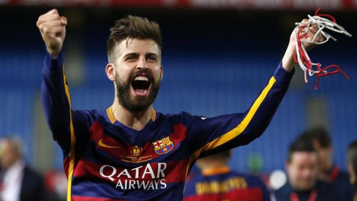 Piqué, con un trozo de red cortada de la portería del Calderón, festeja la Copa.-AP / FRANCISCO SECO