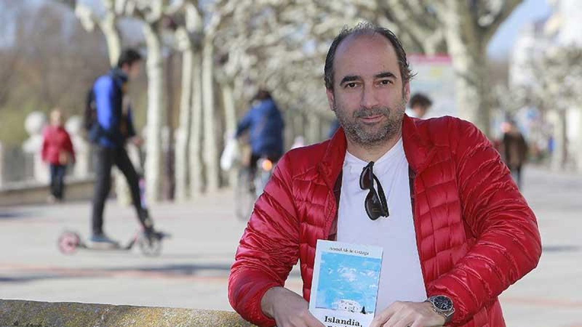 Ismael Ali de Unzaga posa en el paseo del Espolón con uno de los ejemplares de ‘Islandia, noniná’, su primera novela.-Raúl Ochoa