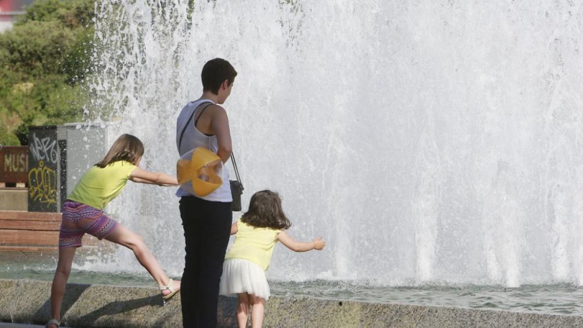 Dos niñas se refrescan junto a su madre en la fuente ubicada junto al Museo de la Evolución.-RAÚL G. OCHOA