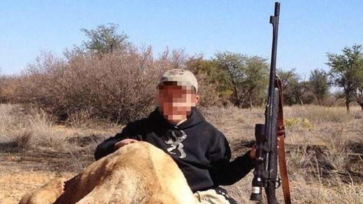 Un niño de siete años sostiene con la mano izquierda un rifle de casa y con la derecha acaricia el lomo del león que acaba de matar.-Foto:   © TWITTER / ALLEN TARPLEY