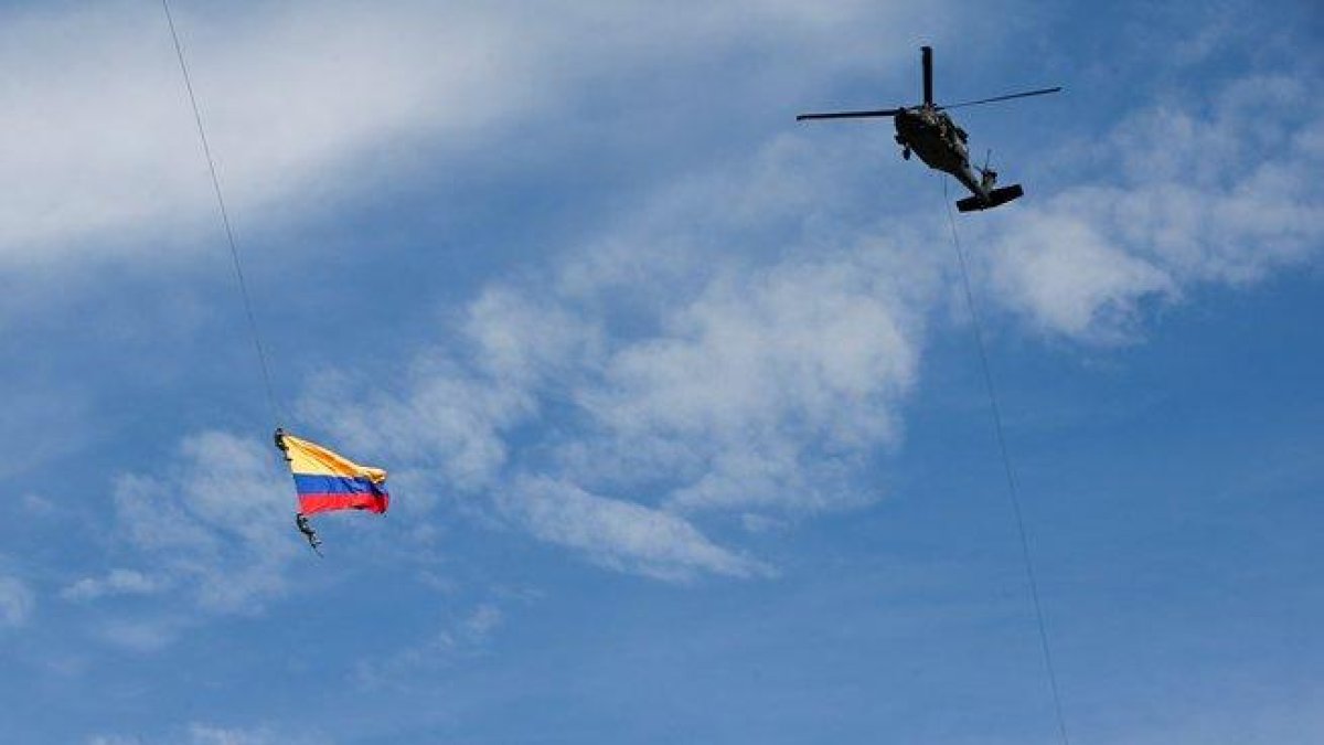 Soldados colombianos colgados de unas cuerdas en un espectáculo militar.-AFP