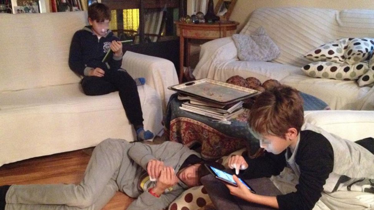 Tres niños de distintas edades se entretienen con dispositivos móviles.-ISRAEL L. MURILLO