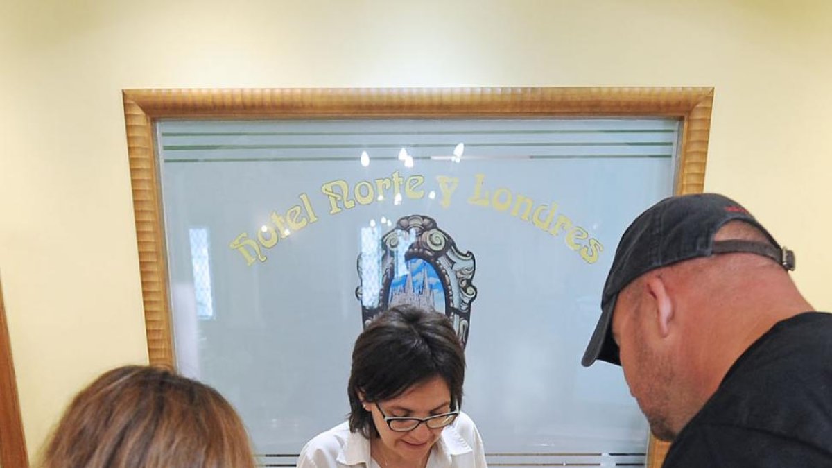 La recepcionista de un hotel de la capital muestra a unos huéspedes los lugares de interés de Burgos.-ISRAEL L. MURILLO