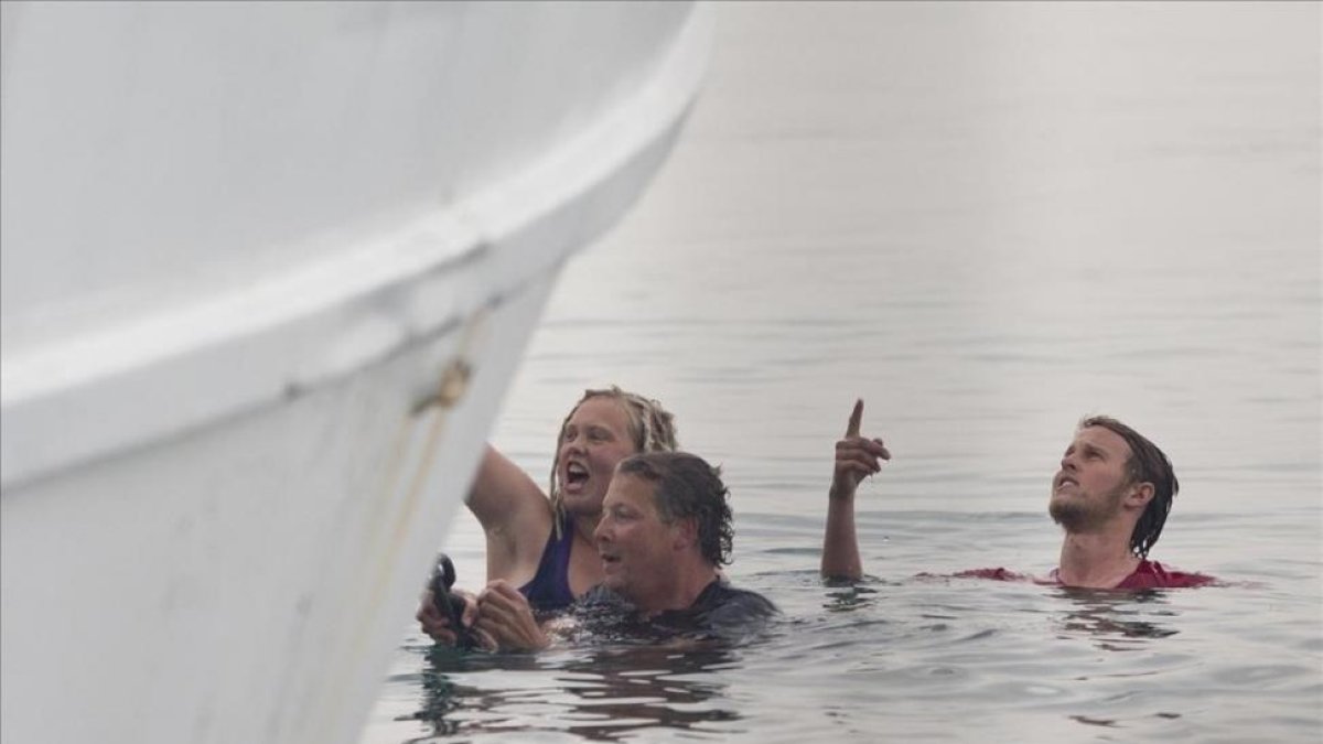 Activistas en el agua intentan impedir la marcha de un ferri que traslada a refugiados de vuelta a Turquía en el puerto de Mitilene (Grecia), en Lesbos.-AP / PETROS GIANNAKOURIS