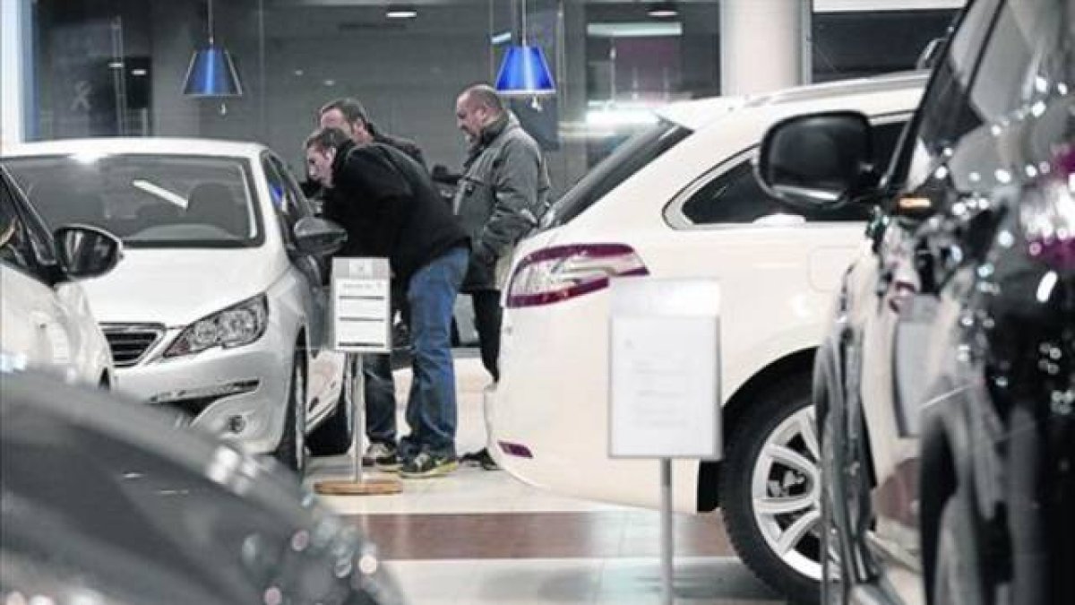 Clientes de un concesionario muestran interés por un modelo a la venta.