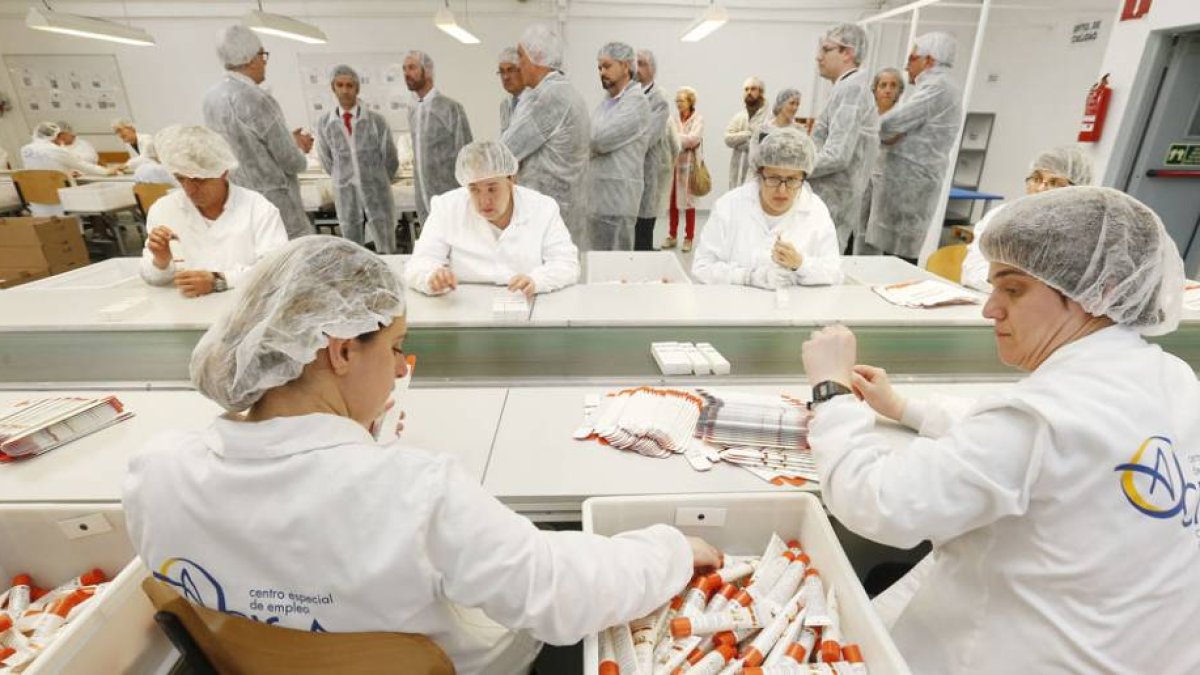 Las autoridades, al fondo de la imagen, visitaron el centro especial de empleo que realiza trabajos para la empresa de cosmética.-RAÚL G. OCHOA