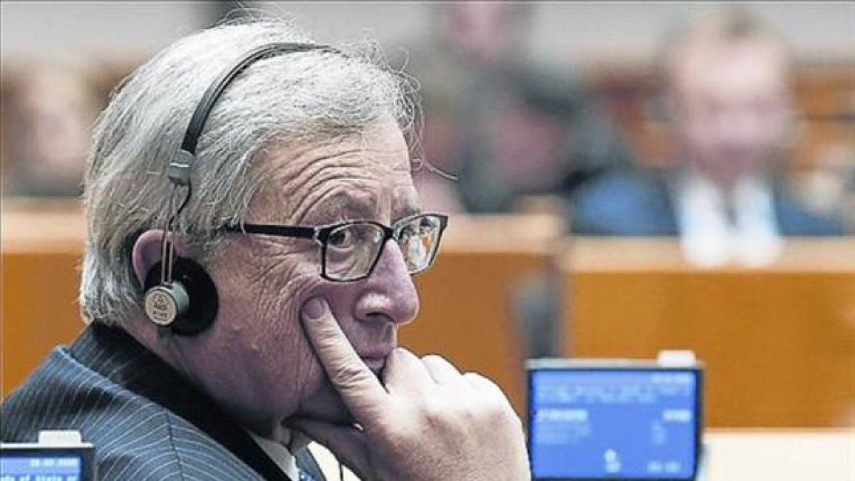 Jean-Claude Juncker, con unos auriculares de traducción en un pleno del Parlamento europeo.-JULIAN WARNAND