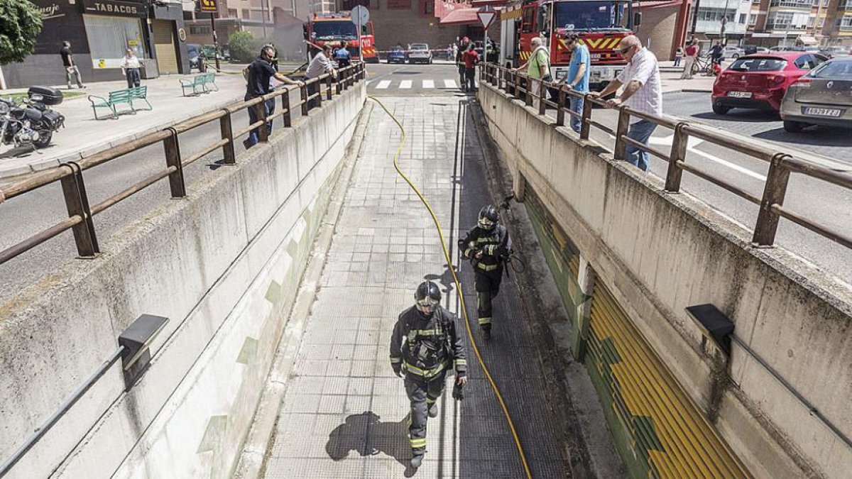 Dos bomberos acceden a la entrada del garaje ante la mirada de los vecinos.-SANTI OTERO