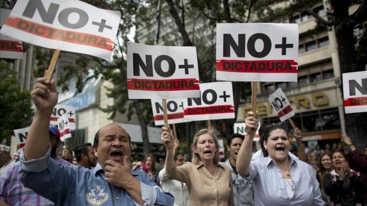 Manifestantes contrarios a Maduro sostienen pancartas en las que reclaman que se acabe la dictadura en Venezuela.-ARIANA CUBILLOS (AP)
