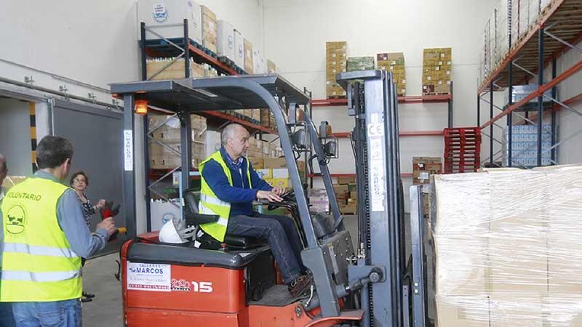 Un voluntario del banco de Alimentos descarga una caja con productos de un camión.-RAÚL G. OCHOA
