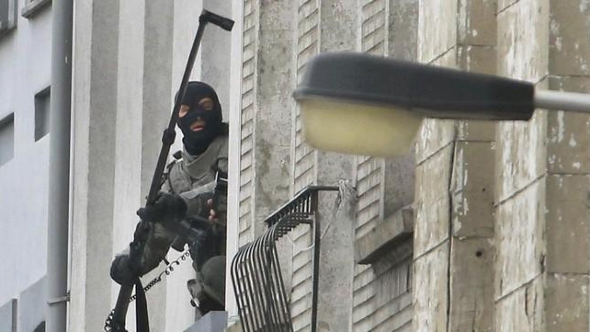 Un agente utiliza una cámera extendida para espiar en el interior de un piso, en Molenbeek, este lunes.-REUTERS / YVES HERMAN