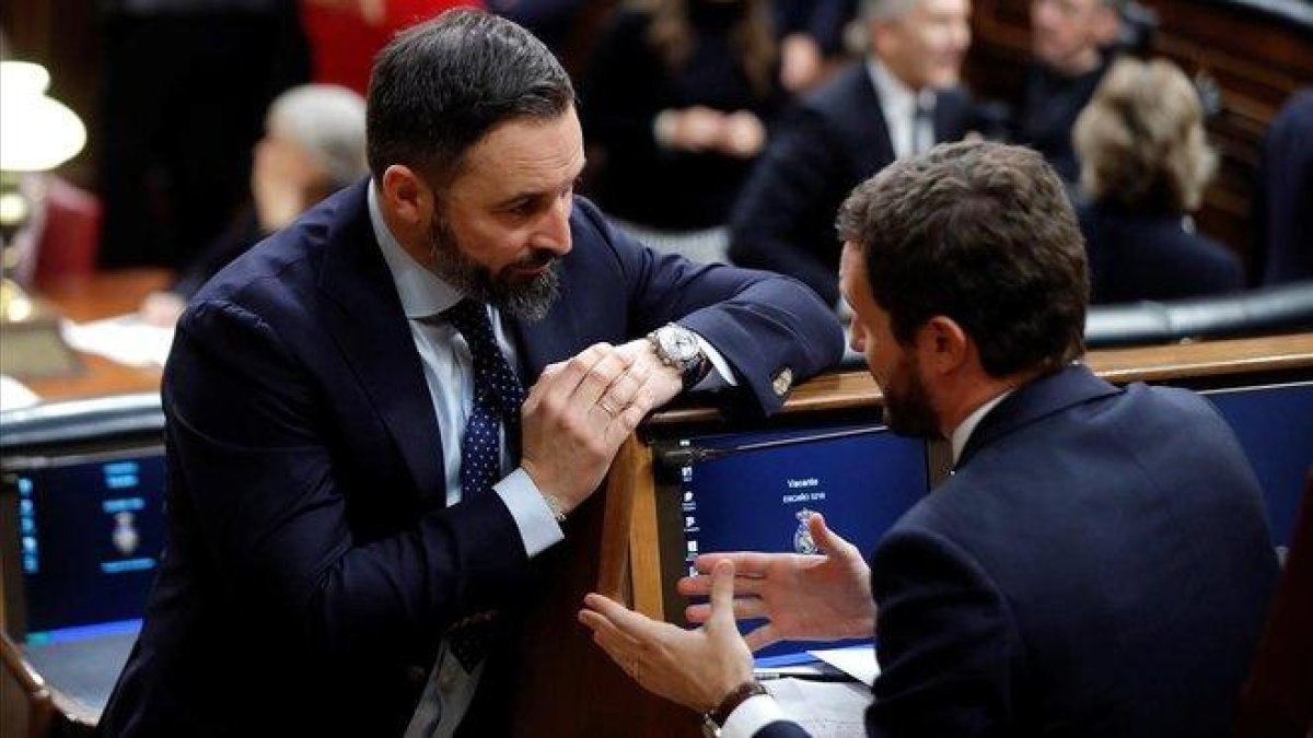 El presidente de Vox, Santiago Abascal, charla con el del PP, Pablo Casado, en el escaño de este en el Congreso.-EFE / BALLESTEROS