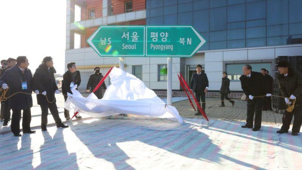Oficiales norcoreanos y surcoreanos destapan dos señales que indican la dirección de las capitales de ambos países en la estación de tren de Panmun en Kaesong.-EPA / KOREA POOL