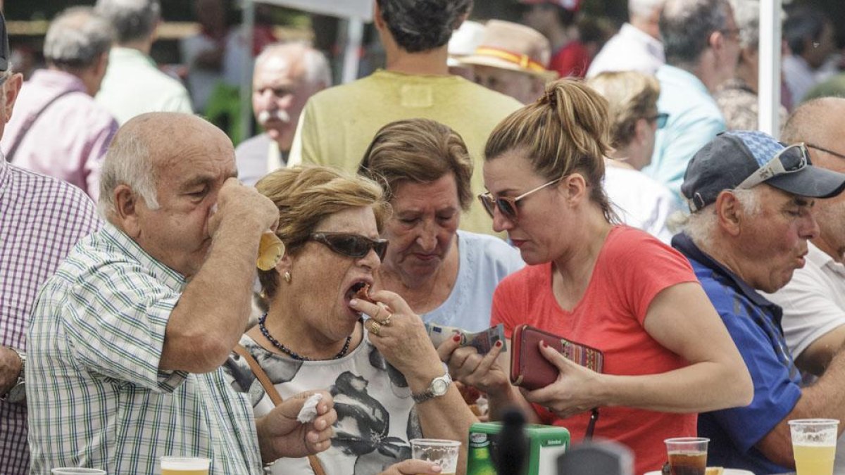 Varias personas degustan un pincho en una de las peñas participantes.-SANTI OTERO