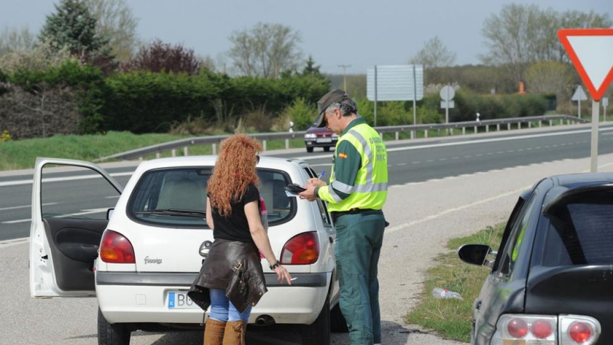 Una agente de la Guardia Civil de Tráfico comprueba la documentación de una conductora en una carretera de Burgos.-ISRAEL L. MURILLO