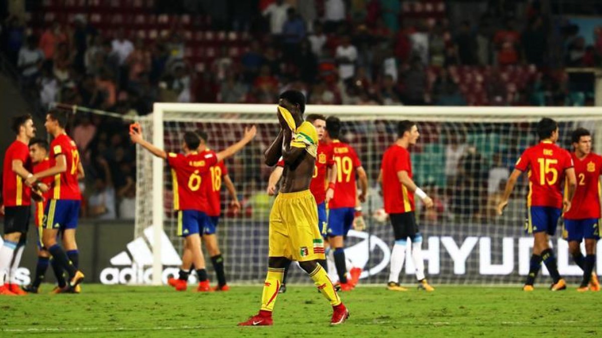 El ghanés Boubacar Haidara (c) reacciona mientras los jugadores de la selección española celebran tras vencer 3-1 a Mali en las semifinales del Mundial sub17 en el D Y Patil Stadium en Bombai, India.-EFE