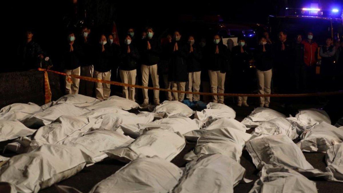 Voluntarios rezan ante los cadáveres de los fallecidos en el accidente de autobús en Taiwán.-REUTERS