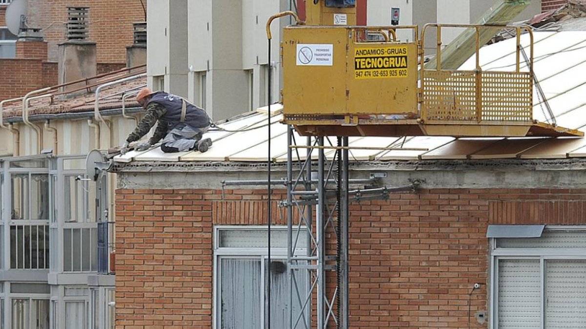 Un trabajador, sobre el tejado de una vivienda.-ISRAEL L. MURILLO