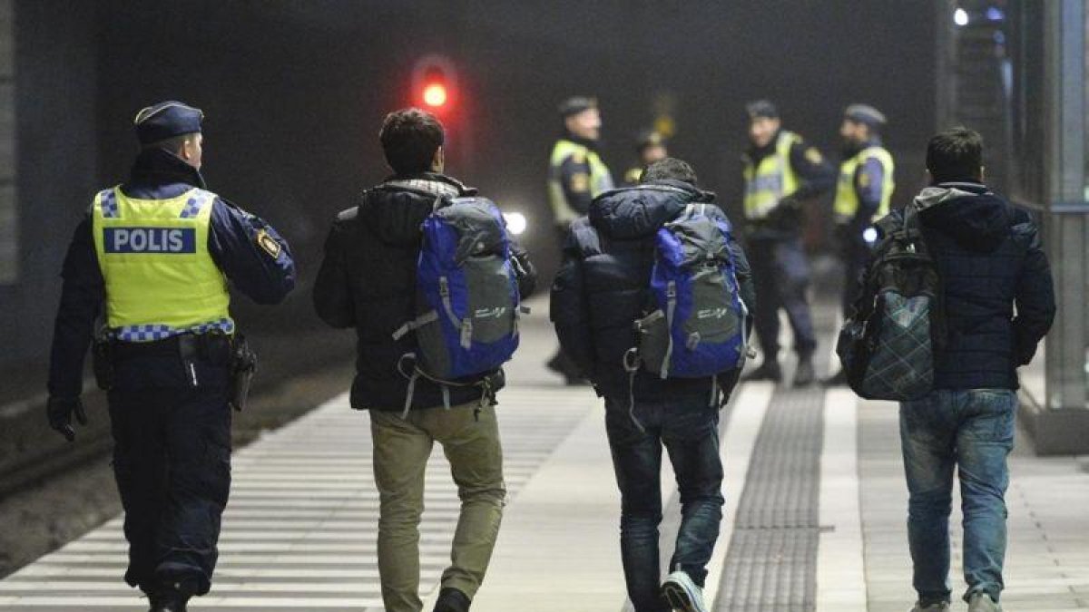 Policías suecos acompañan a dos refugiados en la estación de tren de Hyllie, en Malmo.-REUTERS / JOHAN NILSSON