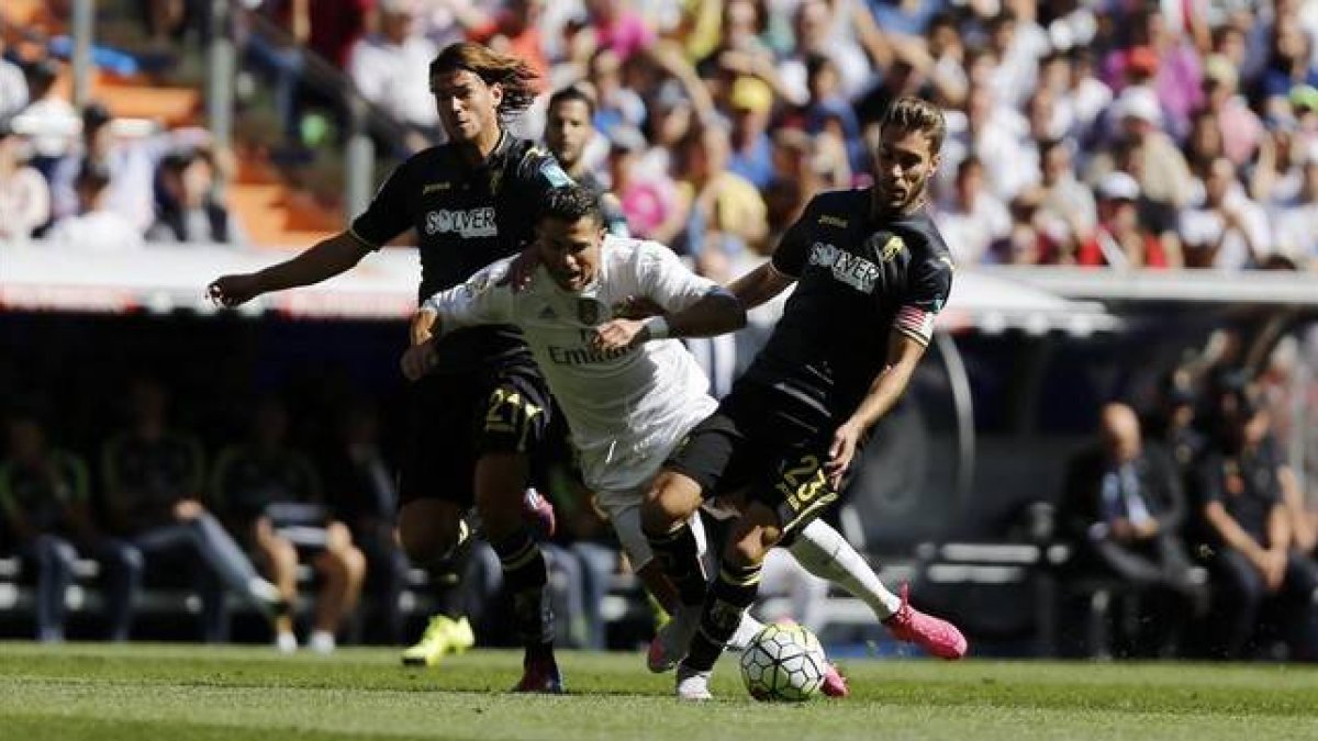 Cristiano Ronaldo cae el suelo entre dos defensas del Granada.-AGUSTÍN CATALÁN