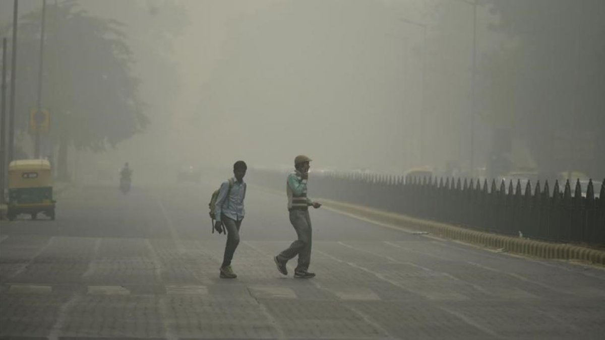 Peatones en medio de una intensa niebla toxica en Nueva Delhi.-AFP / SAJJAD HUSSAIN